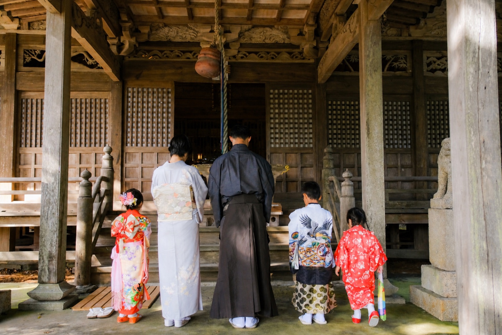 院主夫妻と3人のお子さまが、神社で手を合わせている後ろ姿（着物姿）